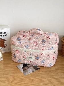 Detailed close-up of pink quilted makeup bag with cute cartoon bear and bunny patterns