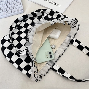 Detail view of lace trim and magnetic closure on checkerboard canvas tote bag