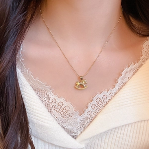 Close-up of a model wearing a gold rocking horse pendant necklace with pearl accents
