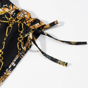 Détail du cordon de serrage latéral sur une mini robe à imprimé baroque et chaîne dorée