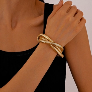 Detail view of a multi-layer gold snake bone wrap bracelet on a female model wrist