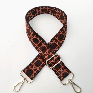 Detail of adjustable geometric patterned fabric shoulder strap with gold metal lobster clasps