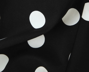Vue détaillée du tissu à pois noirs et blancs avec un fini drapé fluide et lisse