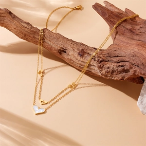 Collier double couche plaqué or avec pendentif cœur en nacre sur socle en bois