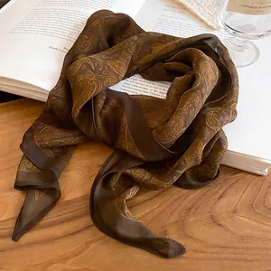 Elegant dark brown paisley silk scarf necklace with golden floral patterns on vintage books