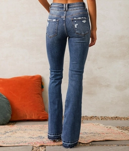 Detail view of high-waist flared jeans featuring distressed back pockets and frayed hems