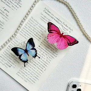 Detailed view of pink and blue butterfly phone grips on an elegant magazine background