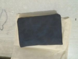 Detail view of a vintage dark blue folding wallet with a matte suede texture on cloth