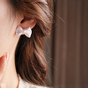 Close-up of elegant pink bow earrings with a silky pearl finish on a female model