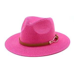 Detail of fuchsia straw fedora hat featuring a brown leather band and gold buckle