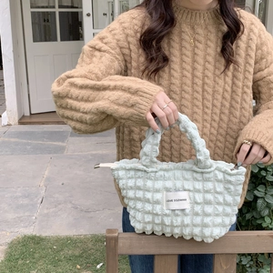 Detail of mint green bubble texture canvas tote bag held by a model in soft daylight
