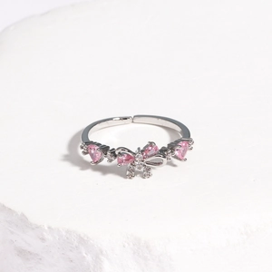 Detailed macro of silver bow ring featuring pink heart-shaped stones and adjustable band