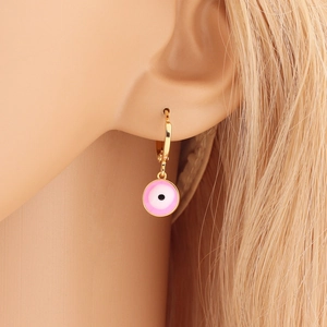 Close-up of pink enamel evil eye charm on gold hoop earring worn by a model