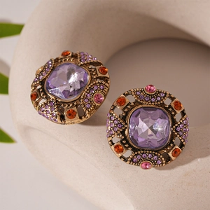 Makro-Detail des Vintage-Goldohrrings mit lila Kristall und bunten Strasssteinen besetzt