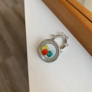 Detail of beaded ring with colorful resin cubes on a silver circular base with elastic band