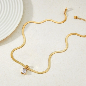 Collier chaîne serpent avec un pendentif en zircon carré sur fond beige texturé