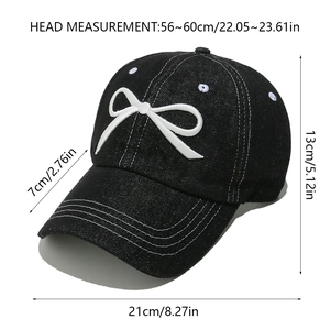 Detail showing white bow embroidery and contrast stitching on black denim baseball cap