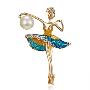 Élégante broche ballerine dorée avec jupe en émail et perle sur fond blanc avec reflet