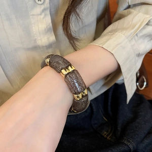 Close-up of geometric acrylic beaded bracelet with gold metal spacers on a wrist