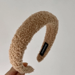 Detail van bruine faux shearling hoofdband met handgemaakt label en zachte textuur