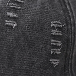 Dettaglio in macro del cotone lavato con strappi stile vintage sul cappello da baseball