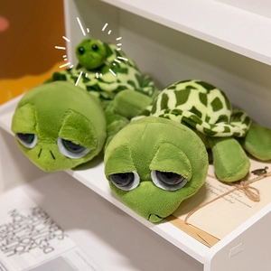 Tre peluche a forma di tartaruga verde con grandi occhi di diverse dimensioni su scaffale