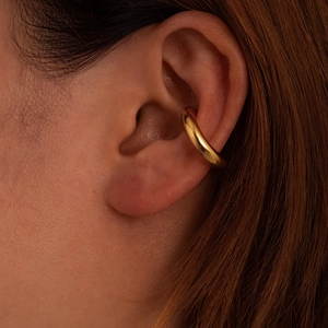 Boucle d'oreille clip ronde en acier inoxydable doré brillant portée sur l'oreille