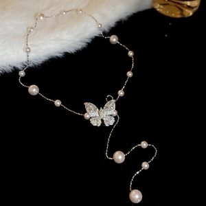 Dettaglio della collana con farfalla in zircone e perle bianche eleganti su velluto