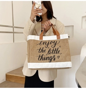 Detail of linen tote bag featuring 'enjoy the little things' calligraphy and PU handles