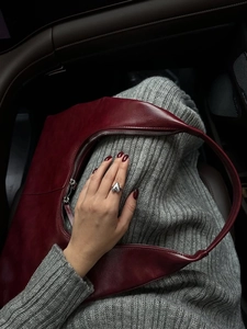 Detailed shot of silver heart ring and burgundy leather bag with grey knit dress