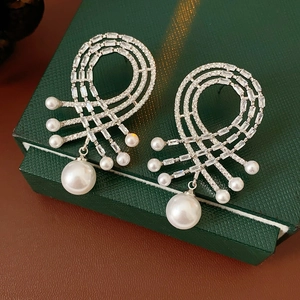 Détail de boucles d'oreilles en argent avec zircons et perles sur un écrin à bijoux vert