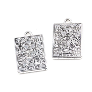Detailed macro view of silver zinc alloy tarot card charms featuring The Sun engraving