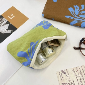 Close-up of leaf pattern cosmetic bag with metal bottles on a white tabletop