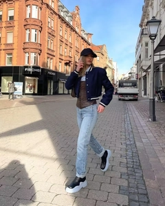 Outdoor street style shot of navy cropped baseball jacket with blue straight-leg jeans