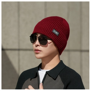 Close-up of deep red knitted beanie showing ribbed texture and black rectangular brand label
