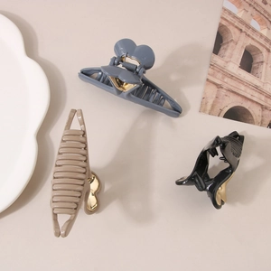 Three elegant heart-shaped hair claw clips in grey blue, cream, and black colors