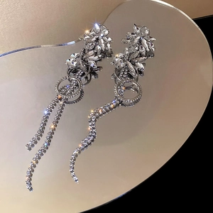 Macro detail of silver tassel earrings with sparkling rhinestones and floral clusters