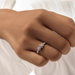 Detailed close-up of a silver floral ring with pink and white zircon gemstones on a finger