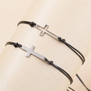Détail de deux bracelets tressés noirs avec pendentifs croix en argent évidés