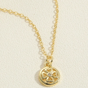 Close-up of golden clover pendant with four hearts and a centered sparkling zircon