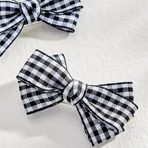 Close-up of black and white checkerboard bow hair clips in soft fabric material