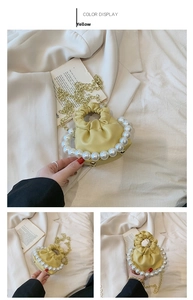Detail of yellow pleated mini bag featuring large pearl handle and gold chain strap