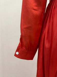 Detail of red chiffon dress featuring fine mesh texture and a white cuff button