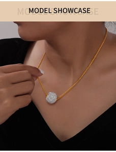 Primo piano della collana in titanio placcato oro con ciondolo a sfera di cristalli pavé