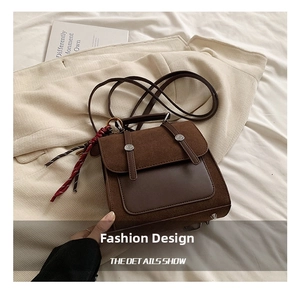 Detalle de bolso bandolera de ante marrón vintage con remaches y colgante de moda tejido