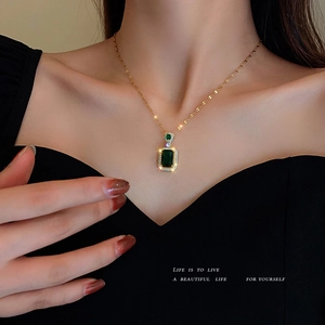 Elegant gold necklace with rectangular emerald green crystal pendant worn by a model