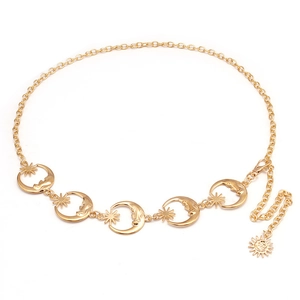 Detail of gold metal waist chain featuring celestial moon and sun charms on white background