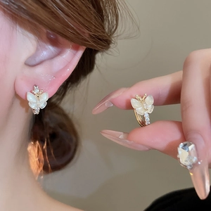 Gros plan sur les boucles d'oreilles papillon dorées avec ailes en opale et zircons