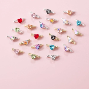 Detailed close-up of colorful heart-shaped rhinestones with metallic wings for nail art