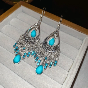 Macro detail of bohemian silver tassel earrings with turquoise stones and blue crystals